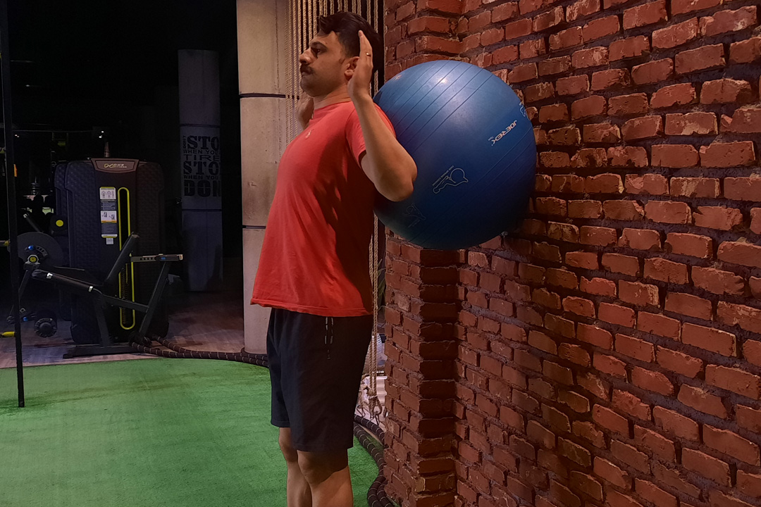 اسکوات با فشار به توپ سوئیسی بین کتف و دیوار